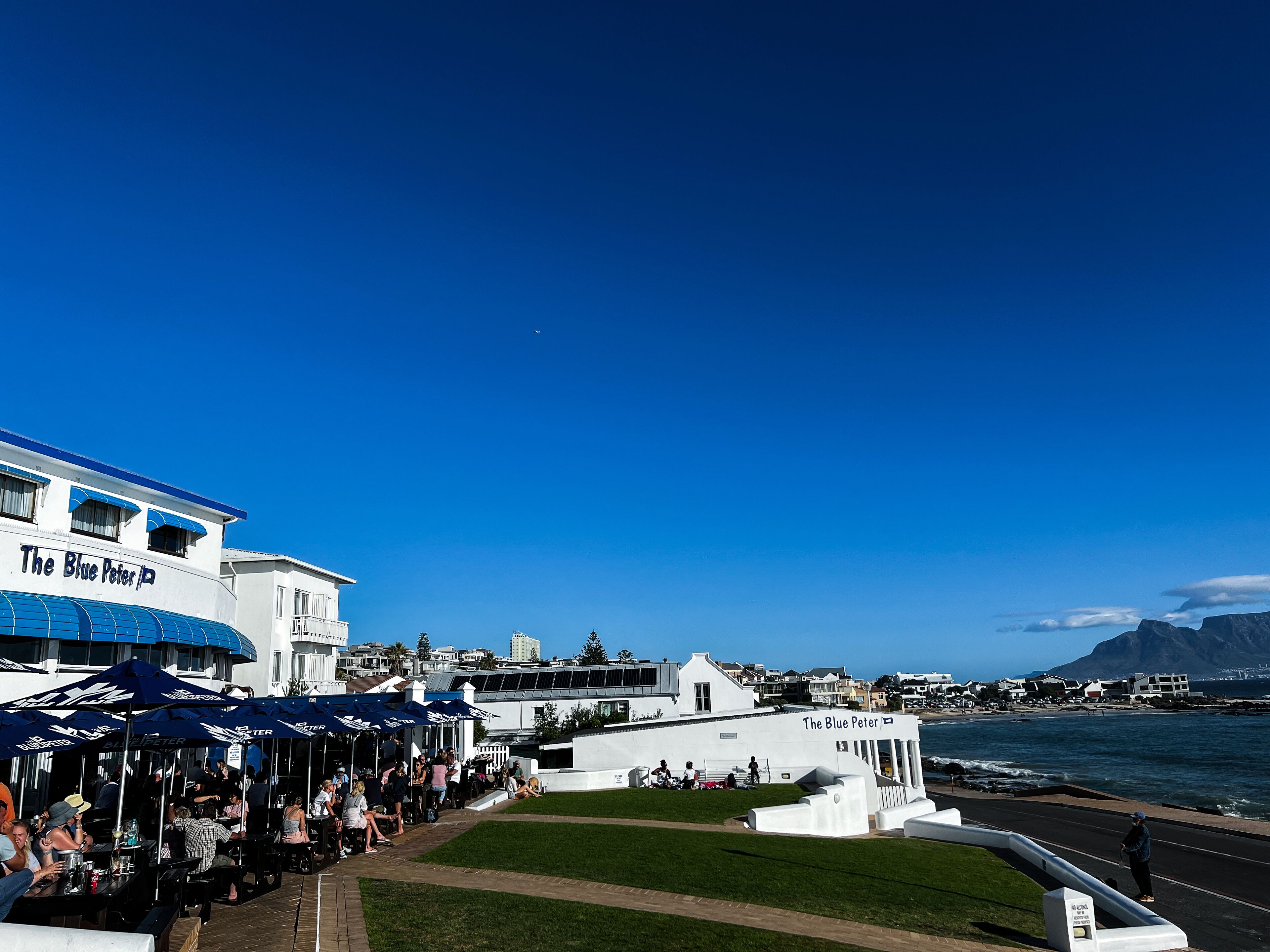 A waterfront restaurant with outdoor seating and a view of the sea.