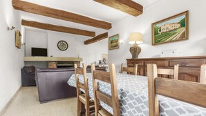 Une pièce comprenant une table à manger, des chaises, un canapé, un téléviseur, une cheminée et un tableau au mur.