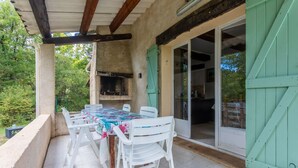 Une terrasse extérieure avec une table et des chaises, un barbecue et une porte-fenêtre coulissante.