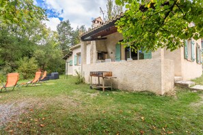 Une maison de campagne avec un patio, un espace salon extérieur et un barbecue.