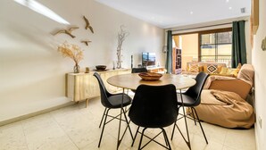 A dining area with a round table, black chairs, a sofa, and a TV. - Seafront Apartment with Pool, Sea Views, Wi-Fi & Air Conditioning (Altea)