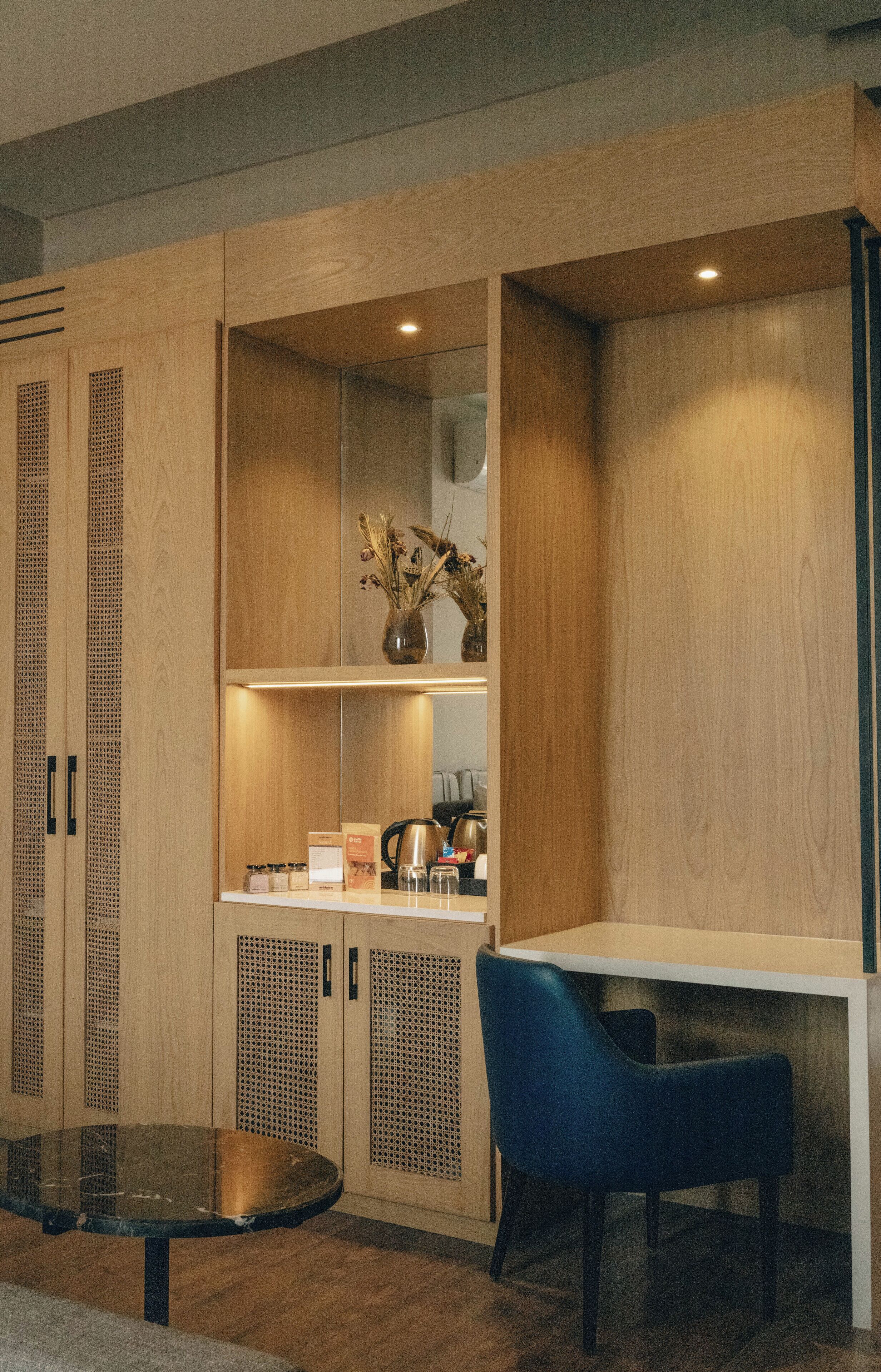 Una cocina moderna con armarios de madera, una cafetera y una silla azul.