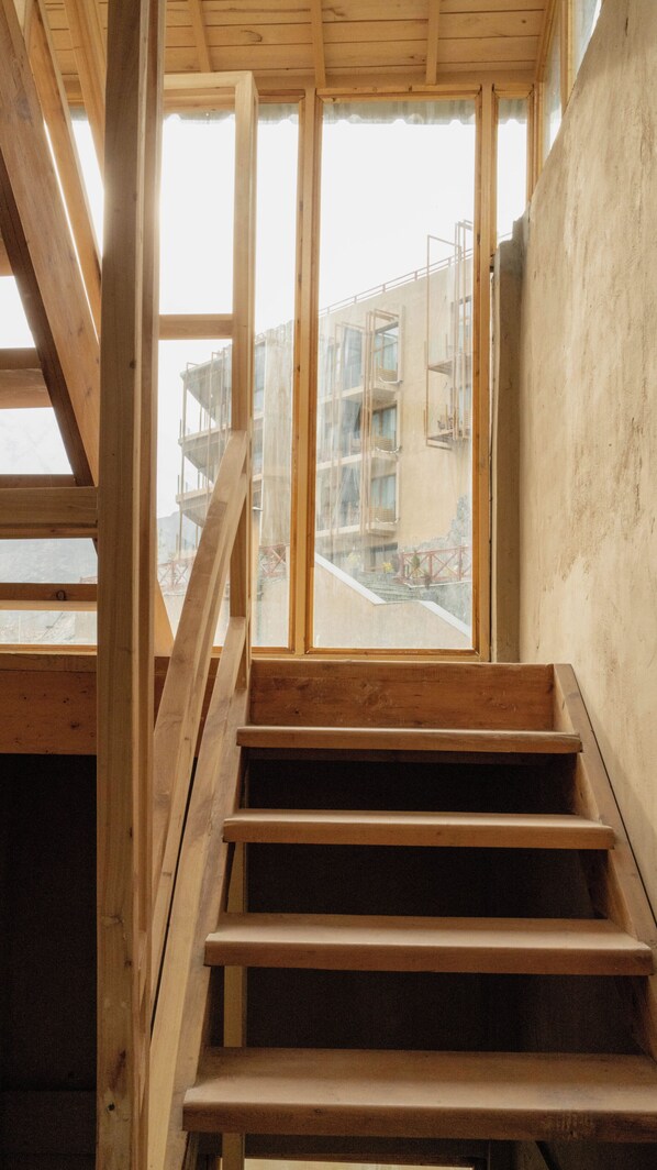 A wooden staircase leading to a window overlooking a construction site. - Ambiance Resort Hunza (Karimabad)
