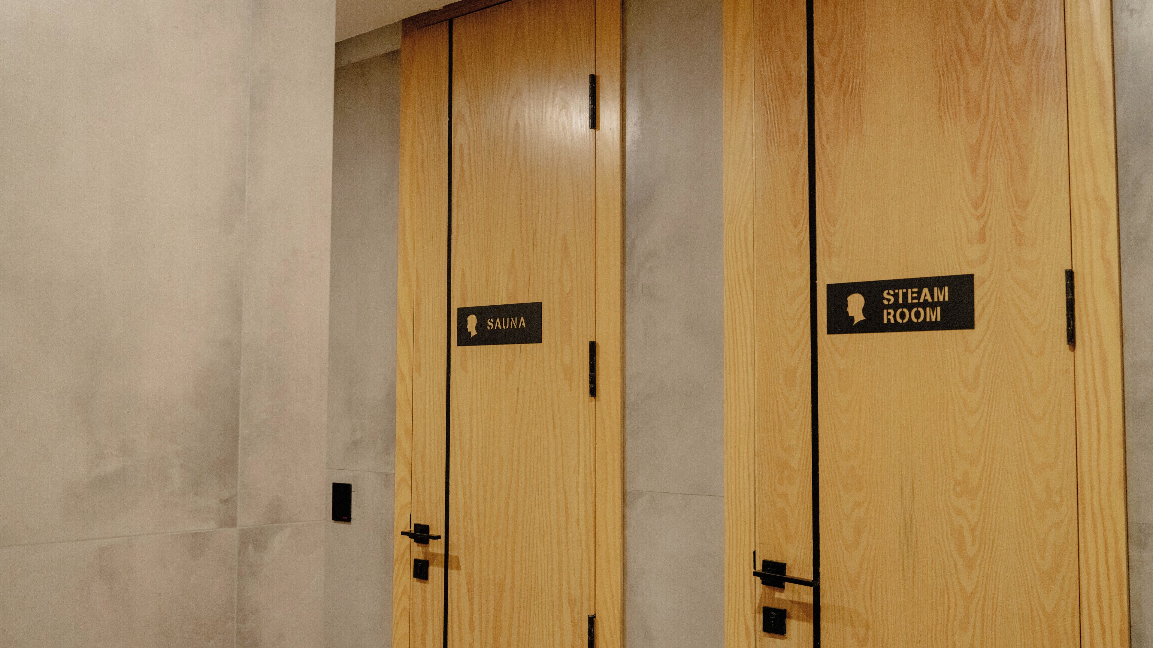 A row of wooden doors with signs indicating a sauna and steam room.