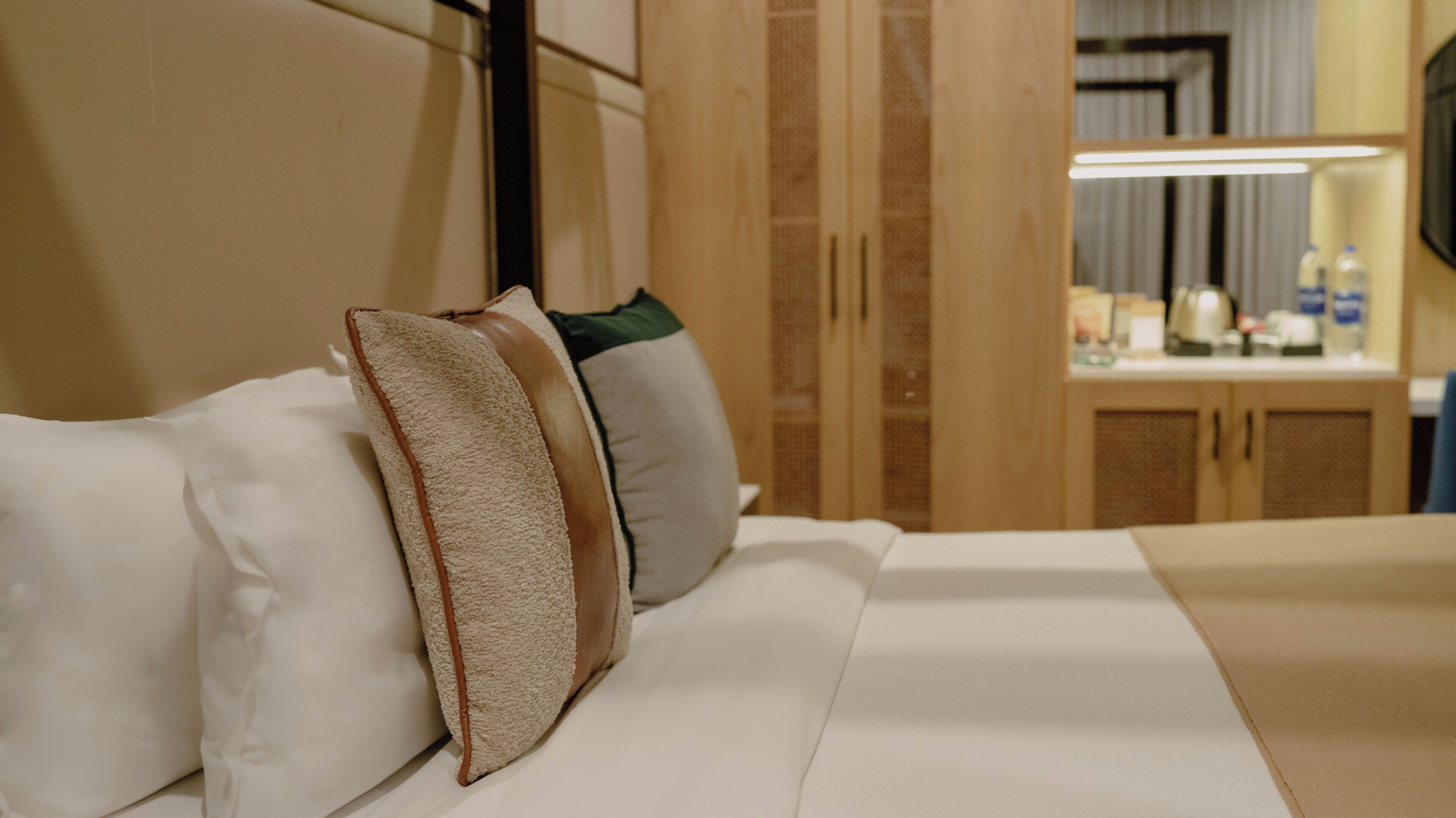 Una habitación de hotel con una cama, almohadas, una mesita de noche y un espejo.
