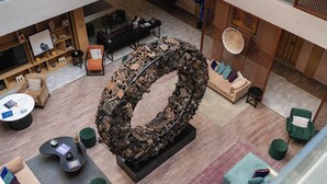 A modern hotel lobby with a large mechanical sculpture centerpiece, comfortable seating areas, and a wooden reception desk. - Ambiance Resort Hunza (Karimabad)