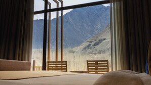 A room with a large window, a bed, and two wooden chairs. - Ambiance Resort Hunza (Karimabad)