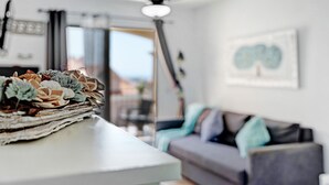 Una sala de estar moderna con un sofá, un ventilador de techo y una ventana con vistas.