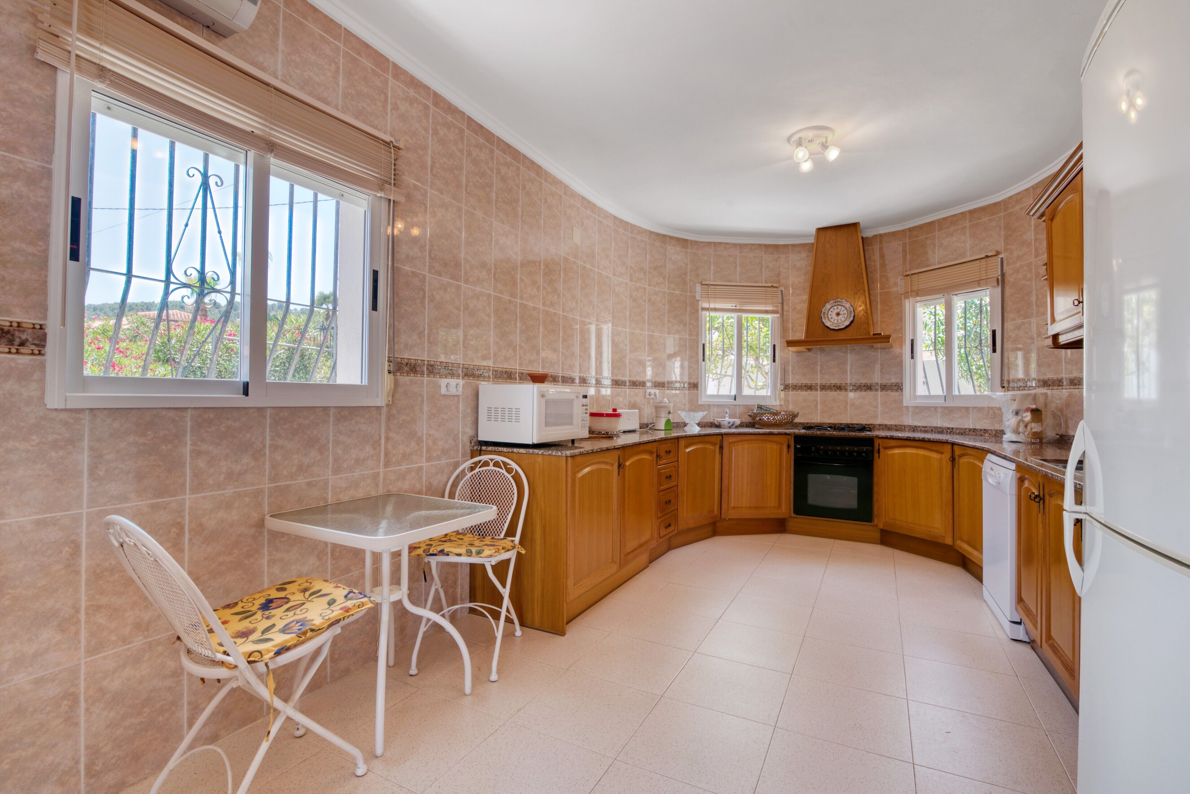 Una cocina con comedor, microondas, pileta y armarios de madera.