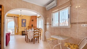 Un coin repas avec une table et des chaises, une vue à travers une arche et un appareil de climatisation fixé au mur.