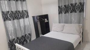 Un dormitorio con una cama individual, un armario y cortinas estampadas.