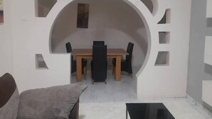 Un área de comedor con una mesa, sillas, un sofá y una mesita con una lámpara.