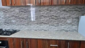 Una cocina con armarios de madera, encimera de granito y salpicadero con diseño de piedra.