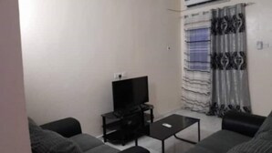 En stue med et fladskærms-tv på et stativ, et sofabord og to sofaer.