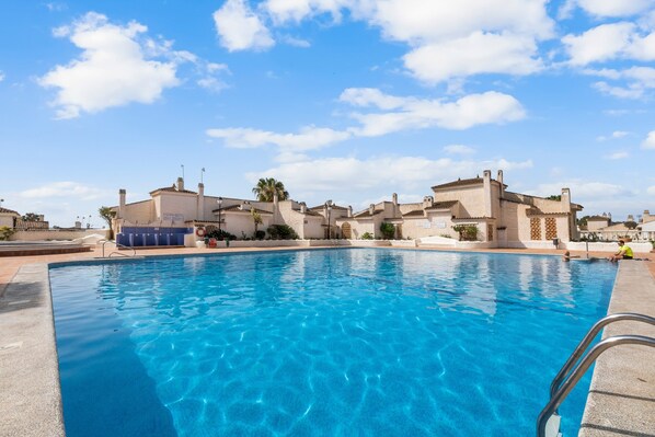 A swimming pool with clear blue water, surrounded by buildings with a uniform architectural style.