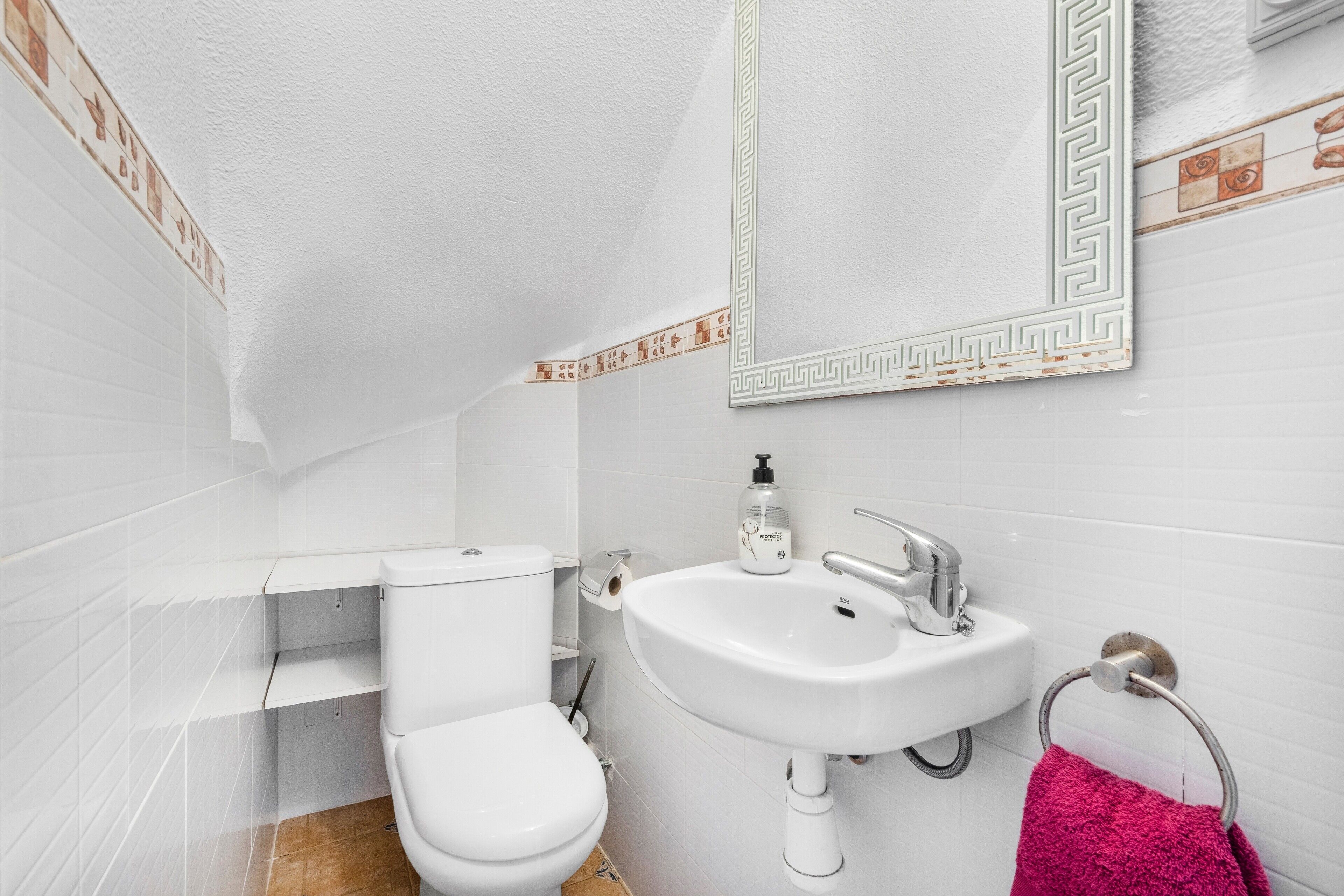 A bathroom with a toilet, sink, and mirror.