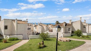 Une cour bordée de bâtiments blancs, un chemin pavé et un lampadaire.