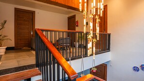 A wooden staircase with a black railing, a potted plant, and a door with the number 303.