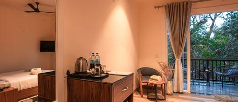 A hotel room with a bed, a desk with a mirror, a coffee maker, and a view of the outdoors.