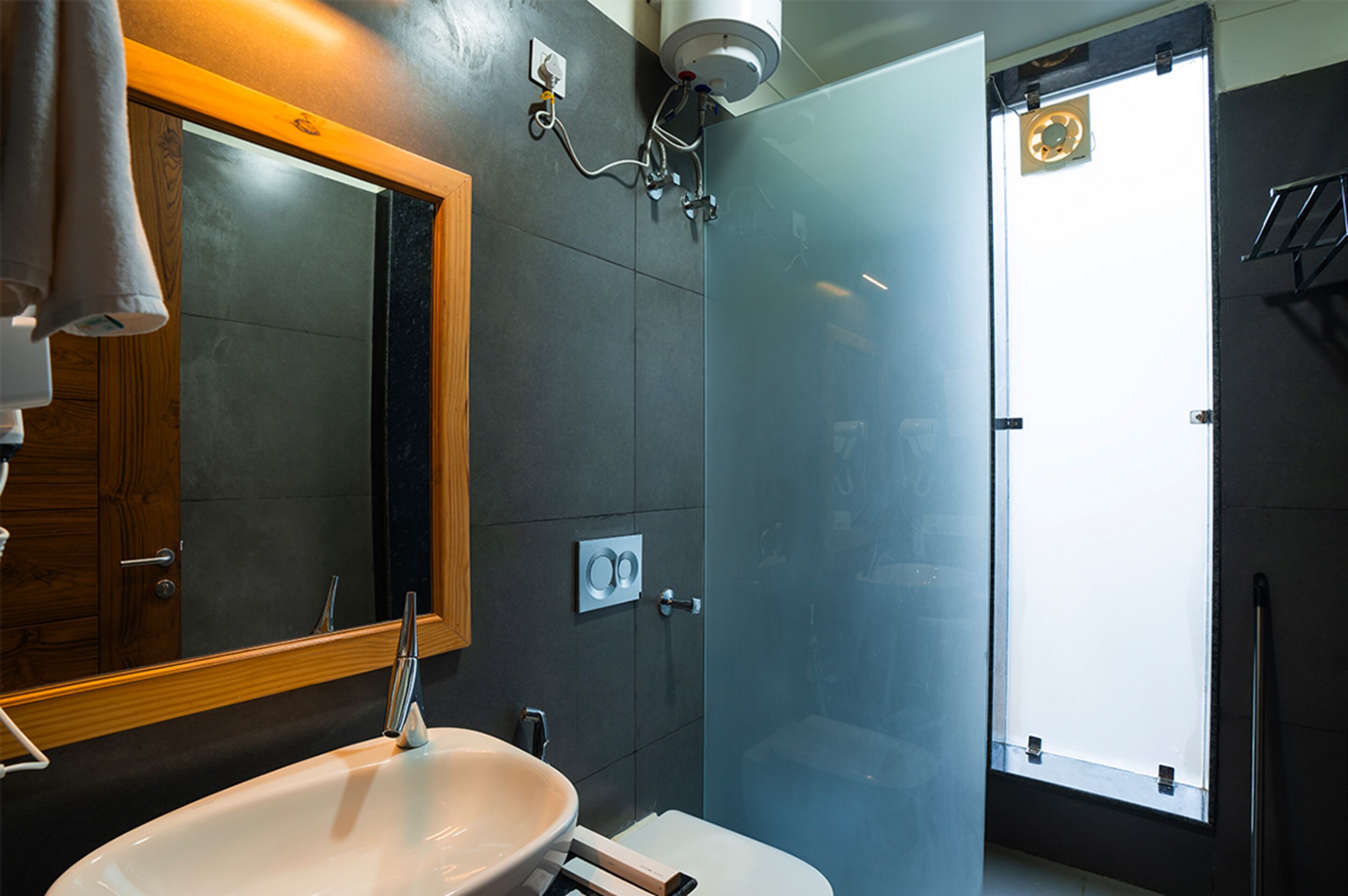A modern bathroom with a large mirror, a white sink, and a shower enclosure.