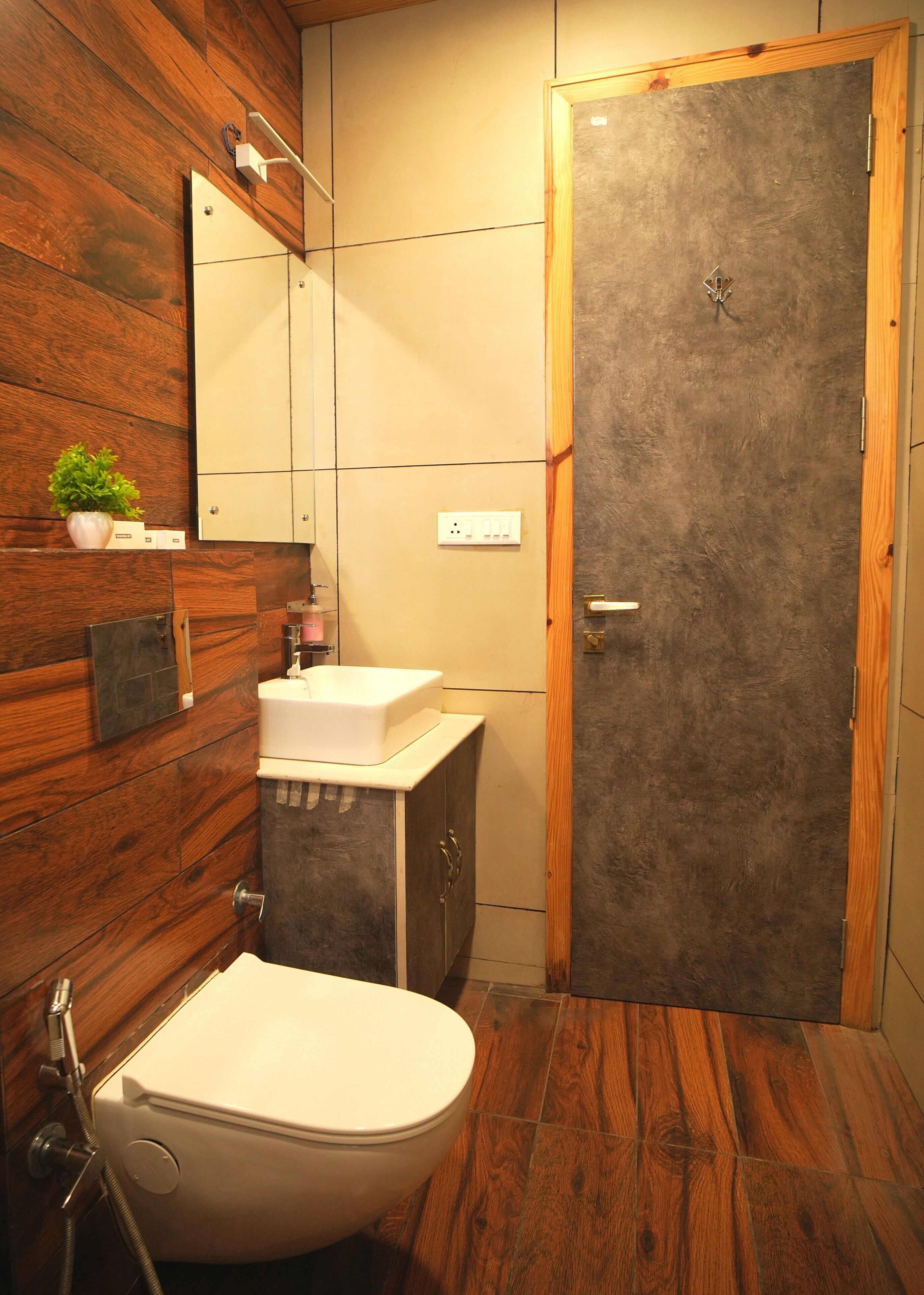 A bathroom with a toilet, sink, mirror, and wooden wall paneling.