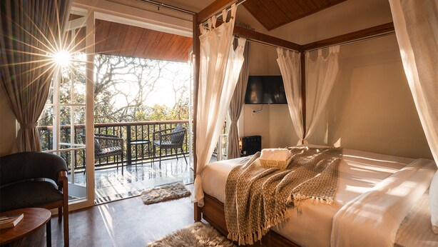 A bedroom with a bed, a chair, a TV, and a balcony with a chair.