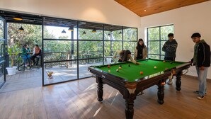 A pool table in a room with large windows, wooden floors, and a ceiling fan.