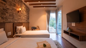 A bedroom with two beds, a stone wall, wooden ceiling beams, a TV, and a balcony with curtains.