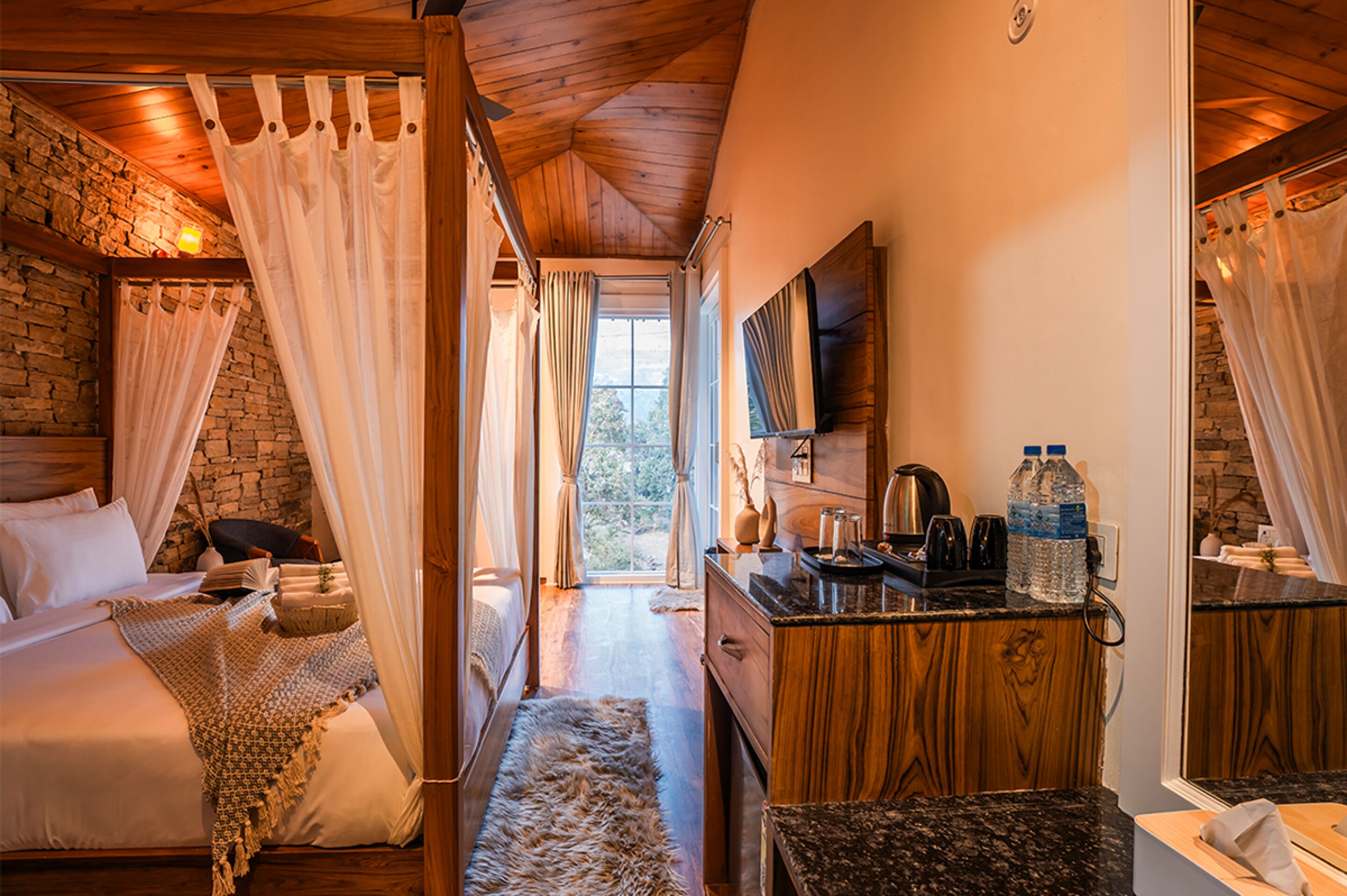 A cozy bedroom with a bed, curtains, and a stone wall.