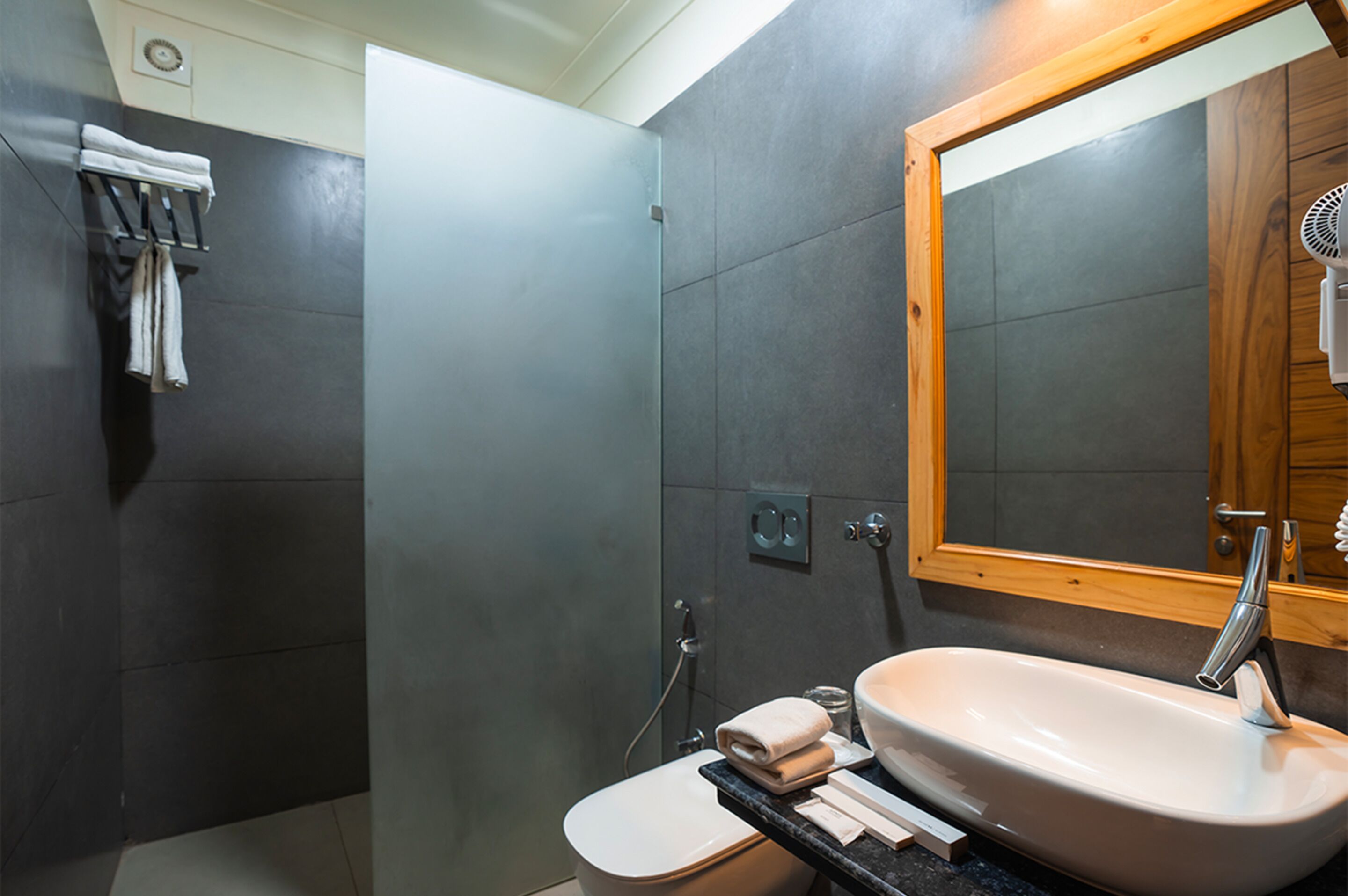 Un baño moderno con ducha, inodoro, lavamanos y un espejo grande.