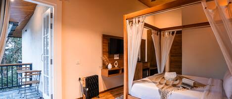 A bedroom with a four-poster bed, a wooden ceiling fan, and a small seating area with a table and chairs.
