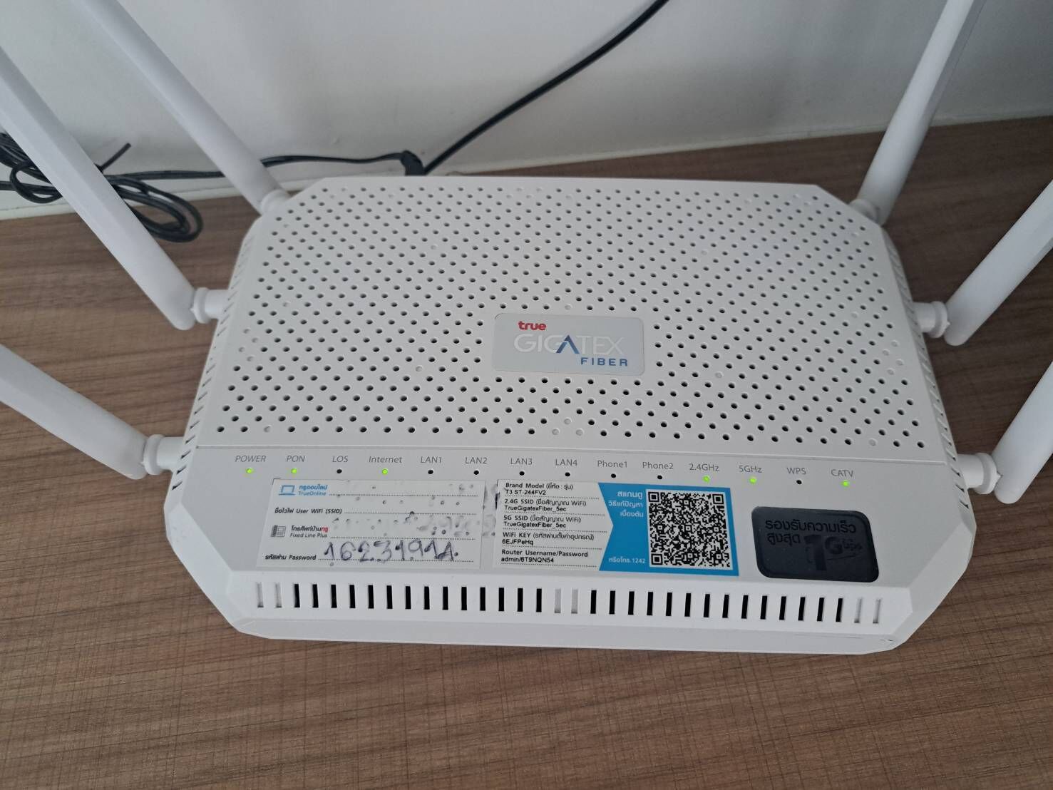 Ein weißer, achteckiger Router mit mehreren Antennen auf einer Holzoberfläche.