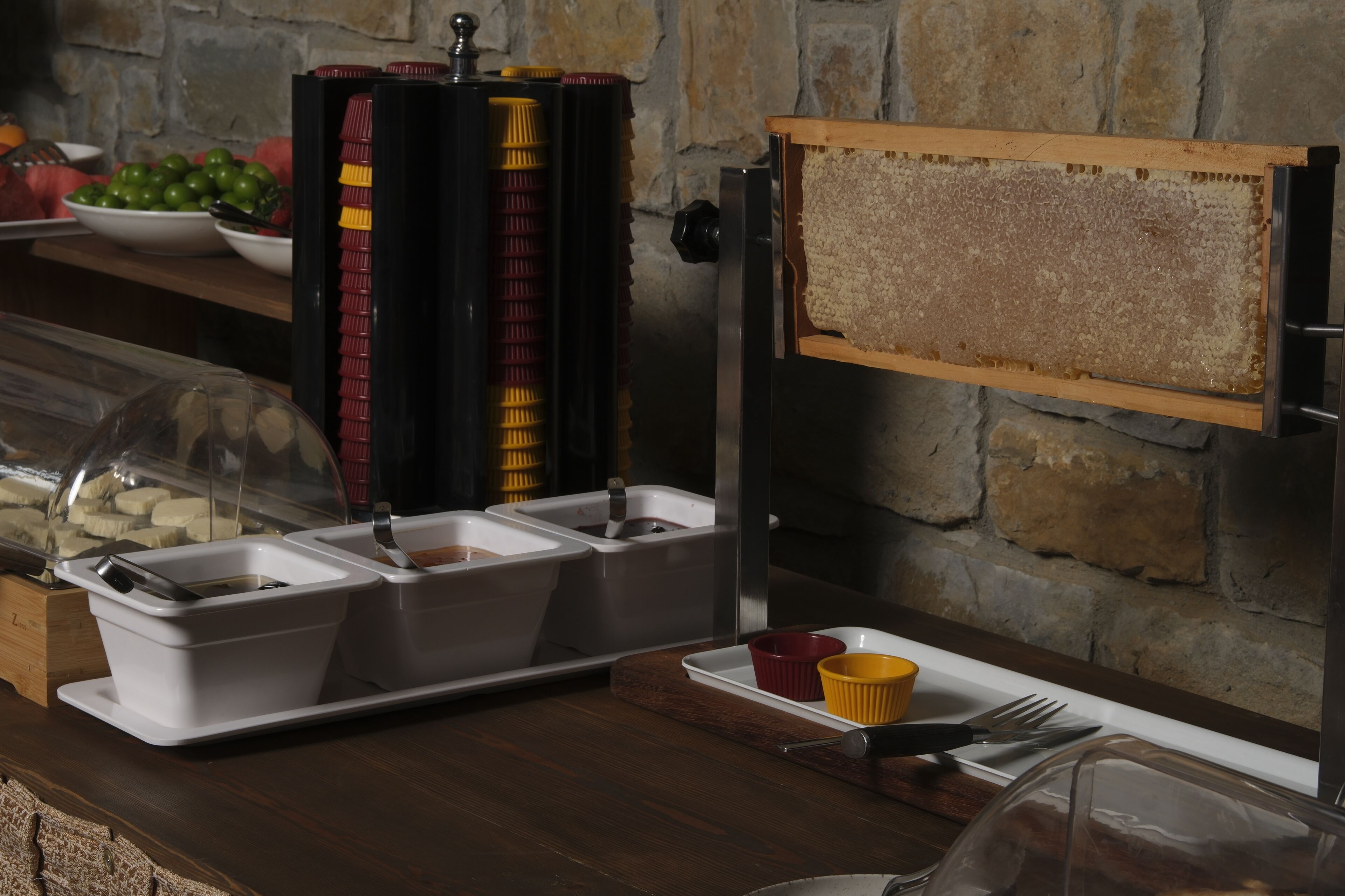 Un buffet avec plusieurs distributeurs de condiments et un récipient de miel en forme de nid d’abeilles.