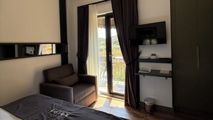 Habitación de hotel con cama, sofá, televisión, escritorio y vistas al exterior.