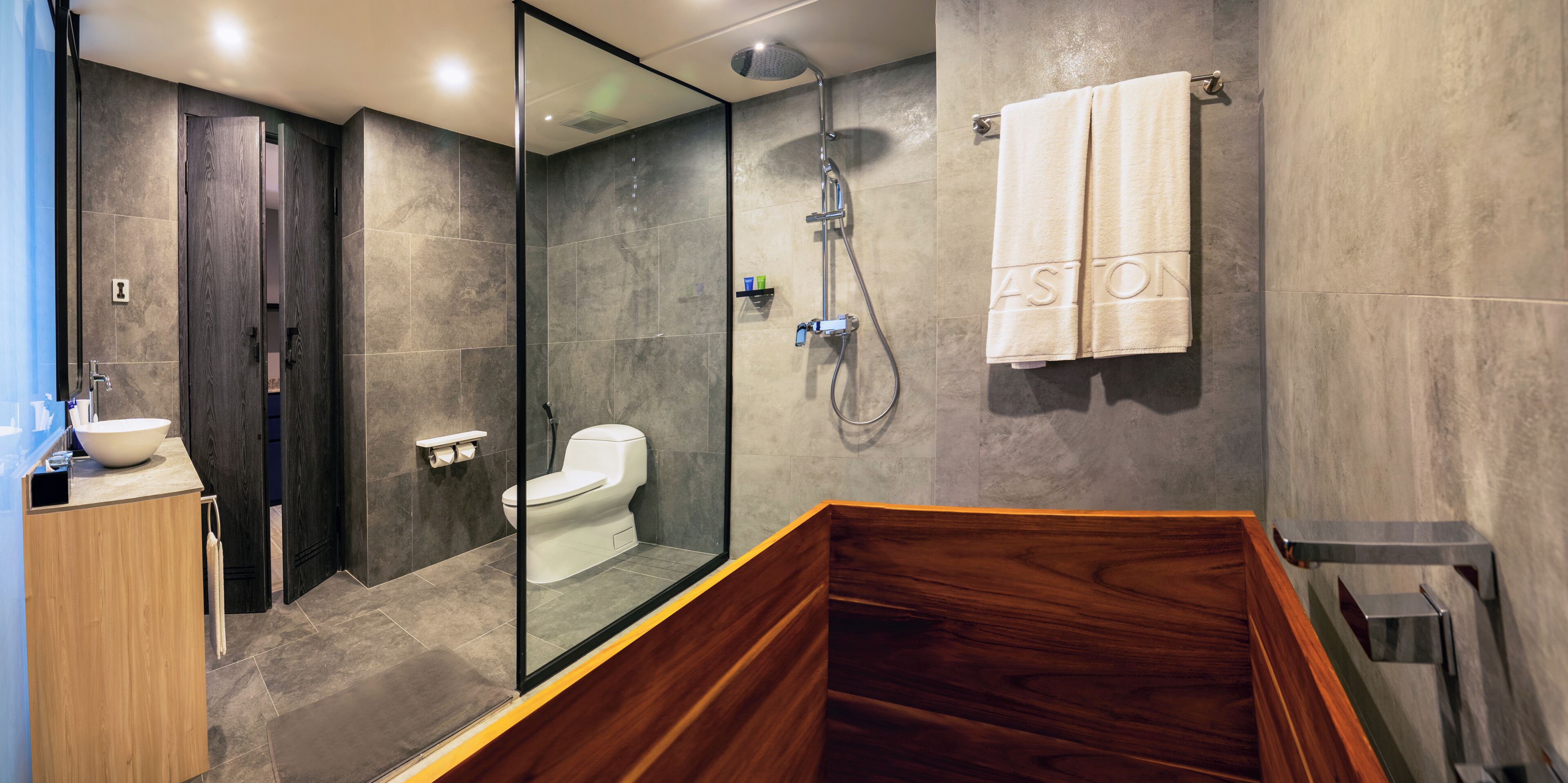 A modern bathroom with a glass-enclosed shower, a wooden bathtub, and a toilet.
