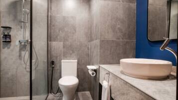 Ein modernes Badezimmer mit einer Glaskabine zur Dusche, Toilette und Waschbecken mit Spiegel darüber.