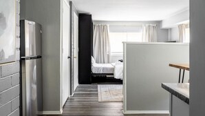 Ein kleines Hotelzimmer mit Küchenzeile, einem Bett und einem Bad.
