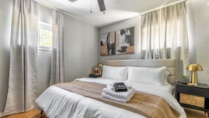 Ein Schlafzimmer mit Bett, Nachttisch, Lampe und Deckenventilator.