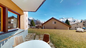 A modern building with a stone facade, a wooden deck, and a view of snow-capped mountains.