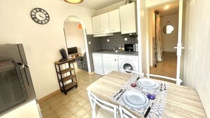 A compact kitchen with a microwave, sink, and washing machine. There's a dining table set with plates and cutlery. - Charming Studio for 2 in Ajaccio, Close to Airport and Amenities (Ajaccio)