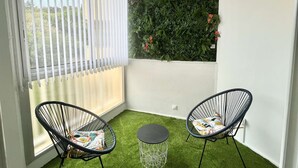 A balcony with two black wire chairs, a small round table, and a green artificial grass floor. - Charming Studio for 2 in Ajaccio, Close to Airport and Amenities (Ajaccio)