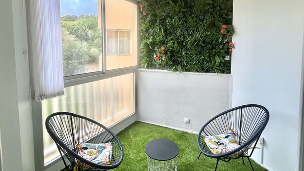 A corner room with a large window, two black wire chairs, a small round table, and a vertical garden wall. - Charming Studio for 2 in Ajaccio, Close to Airport and Amenities (Ajaccio)