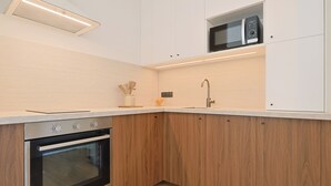 Una cocina moderna con armarios de madera, horno empotrado, microondas y pileta.