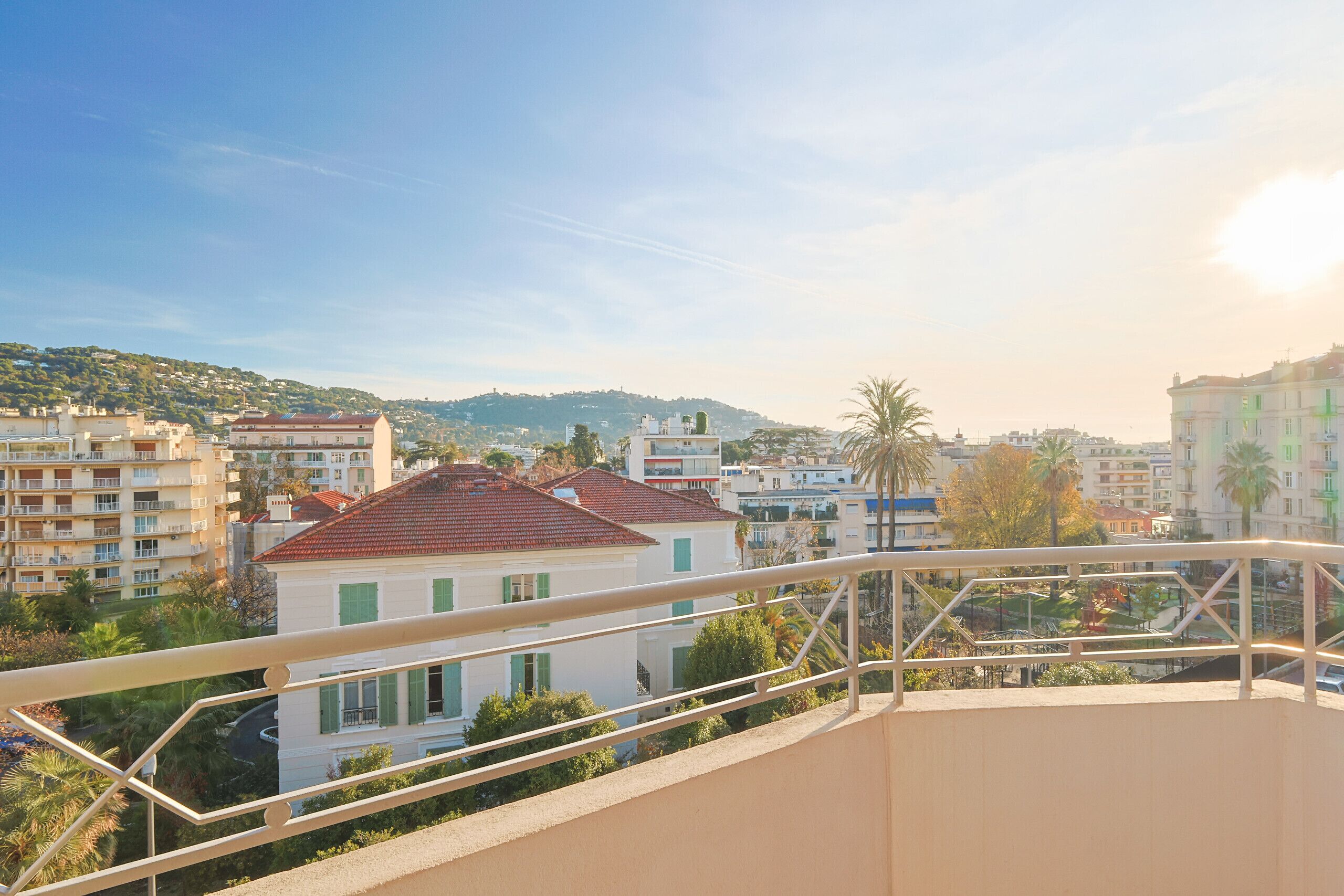 A residential area with buildings, a balcony with a railing, and a clear sky.