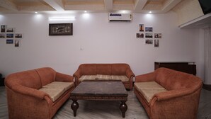 A room with two sofas, a central table, and a ceiling with recessed lighting and an air conditioning unit.