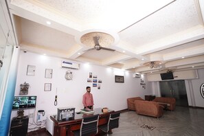 Un bureau bien éclairé, doté d’un ventilateur de plafond, d’un bureau avec des chaises, d’un canapé et d’un réfrigérateur.