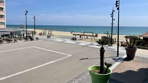 A beachfront area with a café, seating, and a view of the sea.