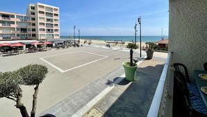 A beachfront view with a hotel, outdoor seating, and a clear sky.