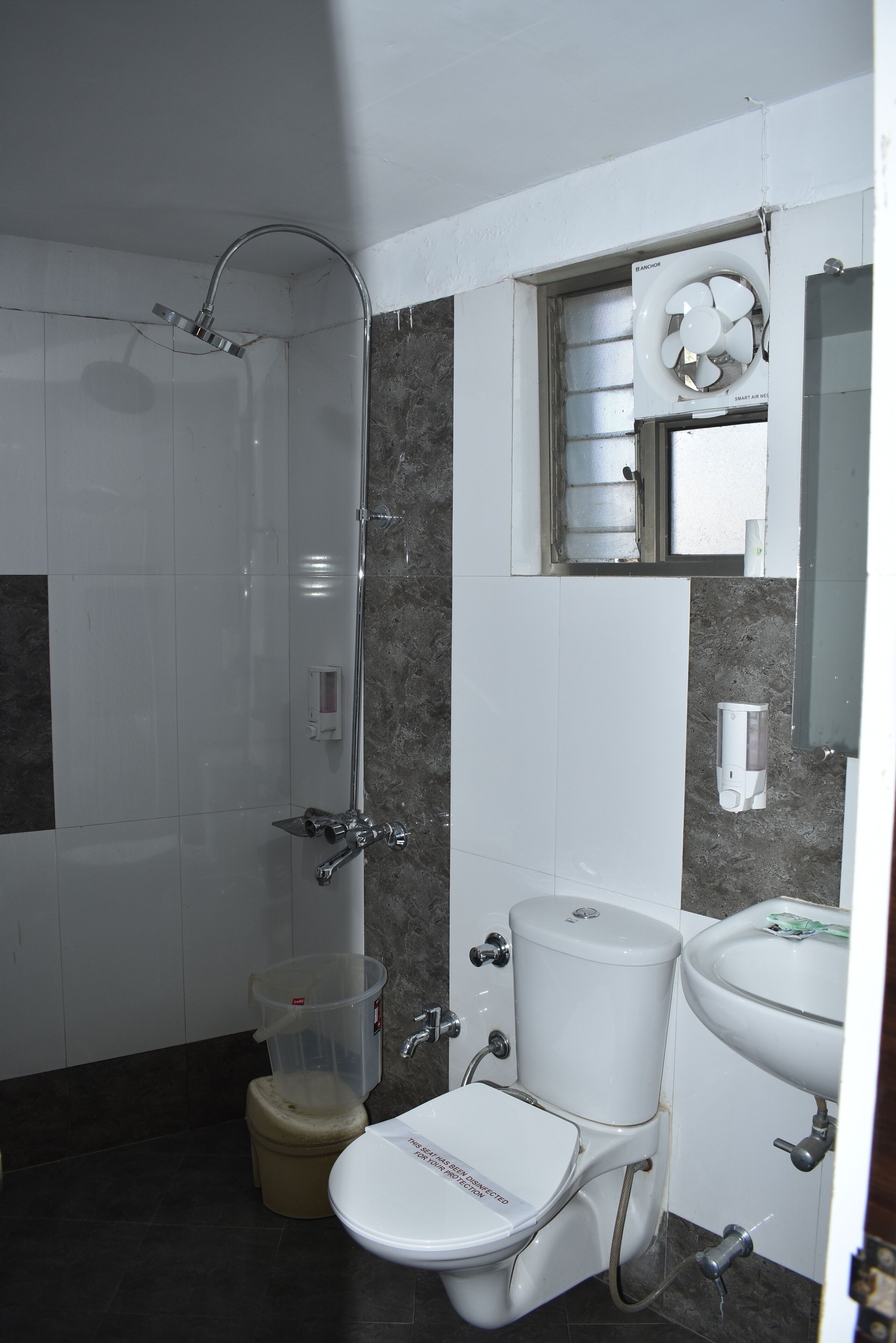 A bathroom with a shower, toilet, sink, and a window.