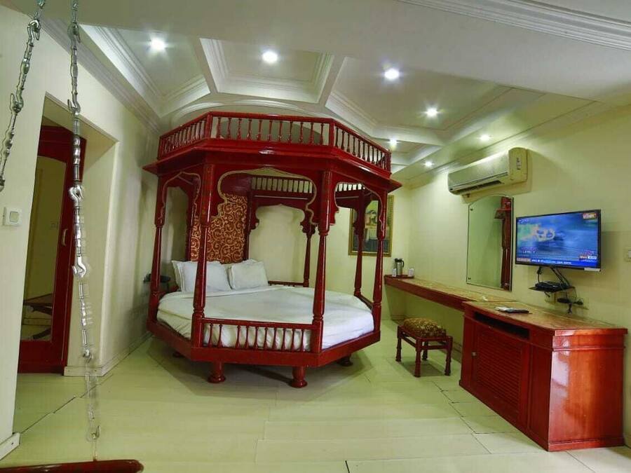 Una habitación con una cama con dosel, un escritorio con computadora, televisor y aire acondicionado.